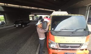 Anggota Dirlantas Polda Jatim membagikan bendera merah putih ke Sopir truk.